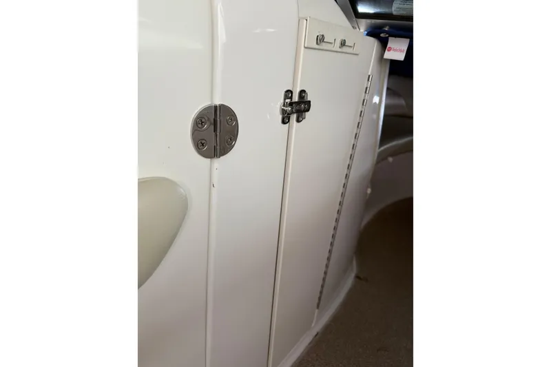 Slide: The Image of 2005 Chaparral Sunesta 236 boat interior with white storage compartment and metal hinge. - 5