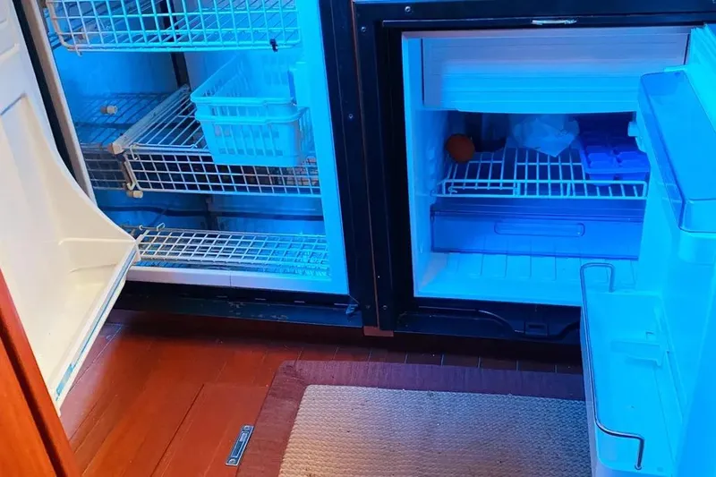 Slide: The Image of Refrigerator interior on 2012 Hunter Aft Cockpit 50 yacht, featuring wire shelves and blue lighting. - 32