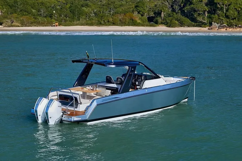 Slide: The Image of Schaefer V34 2027 boat cruising on clear blue water near a lush green shoreline. - 3