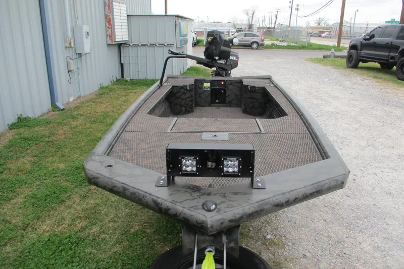 Slide: The Image of 2026 Gator Tail 1854 Extreme boat with camo design, parked outdoors near a building. - 2