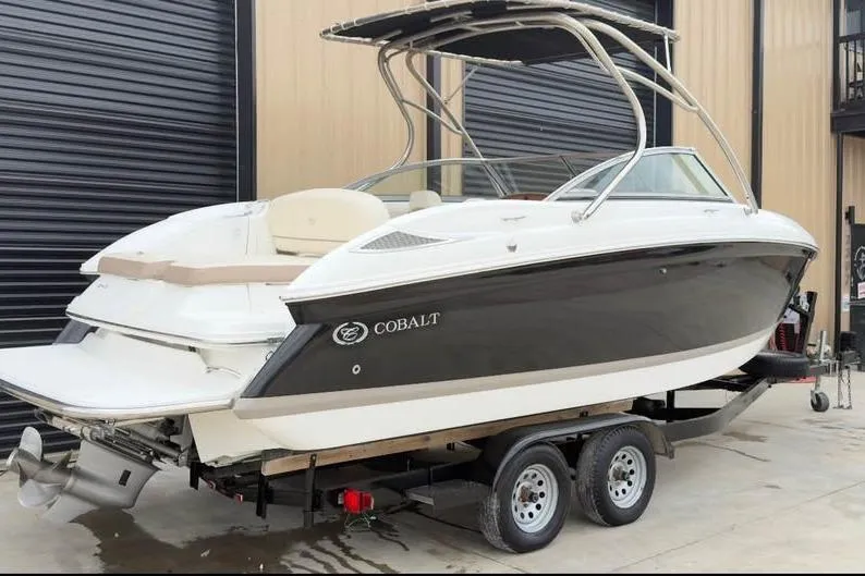 Slide: The Image of 2010 Cobalt 242 boat on trailer, parked near a building. - 11