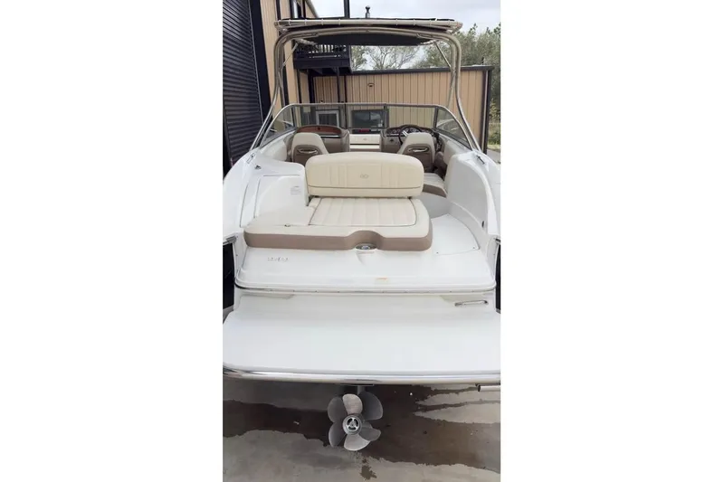 Slide: The Image of 2010 Colbalt 242 boat with beige seating and sleek design, docked near a building. - 12