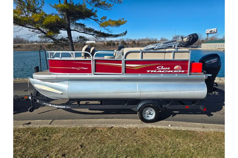 Slide: The Image of 2024 Sun Tracker Bass Buggy 16 XL Select pontoon boat by a lakeside. - 9