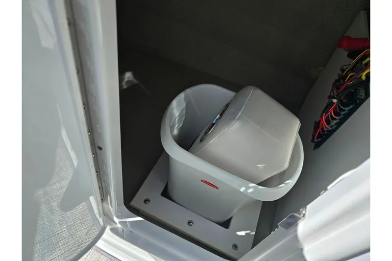 Slide: The Image of 2020 Crownline Eclipse E235 boat storage compartment with wiring and a white container. - 18
