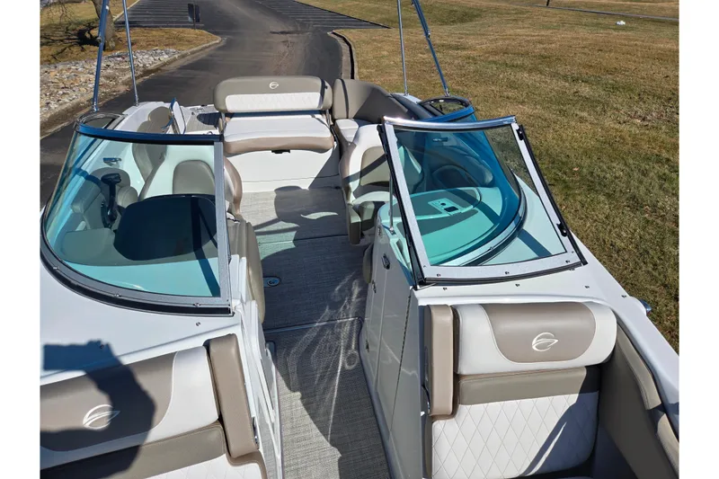 Slide: The Image of 2020 Crownline Eclipse E235 boat interior with seating and windshield, parked on grass. - 25