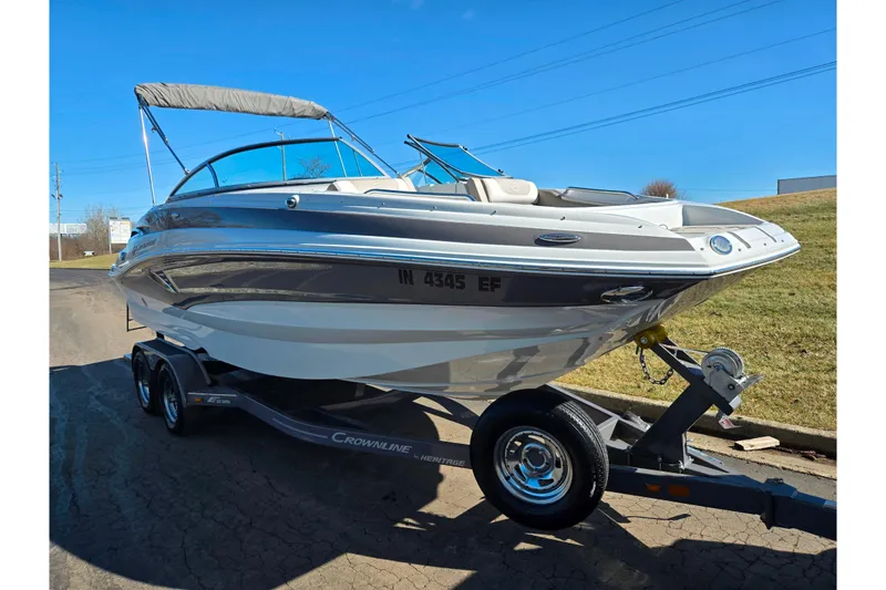 Slide: The Image of 2020 Crownline Eclipse E235 boat on trailer, parked outdoors under clear blue sky. - 5