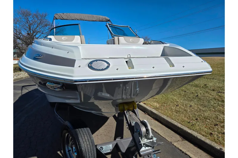 Slide: The Image of 2020 Crownline Eclipse E235 boat on trailer, parked outdoors under clear blue sky. - 6