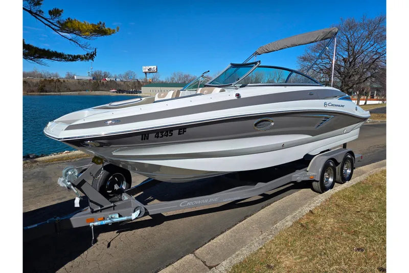 Slide: The Image of 2020 Crownline Eclipse E235 boat on trailer by a lake, under clear blue sky. - 8