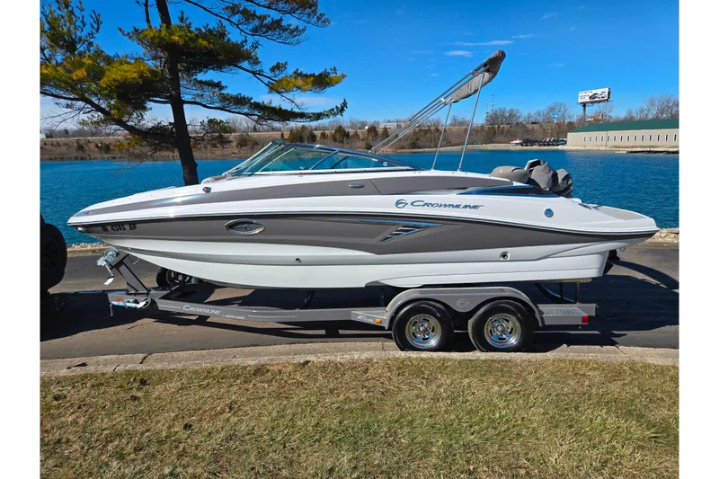 Slide: The Image of 2020 Crownline Eclipse E235 boat on trailer by a lake, under clear blue sky. - 9