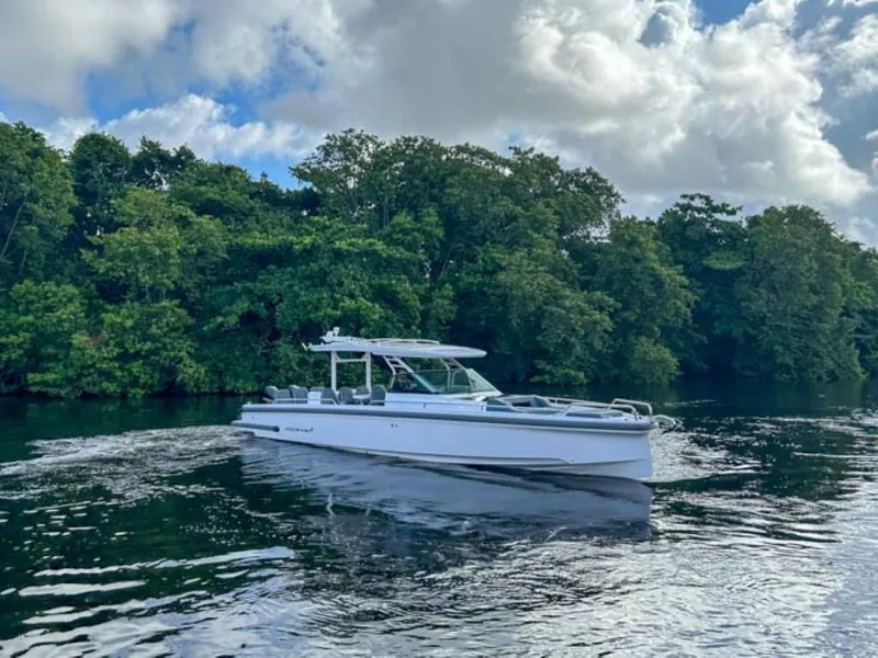 Slide: The Image of 2024 Axopar 37 Sun Top boat cruising on a serene river with lush green trees. - 2