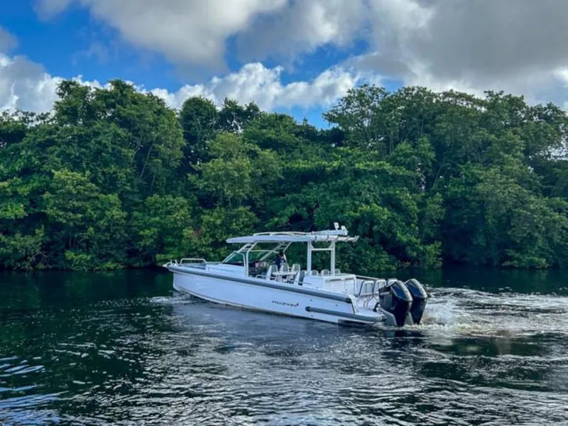Slide: The Image of 2024 Axopar 37 Sun Top boat cruising on a river with lush green trees. - 5