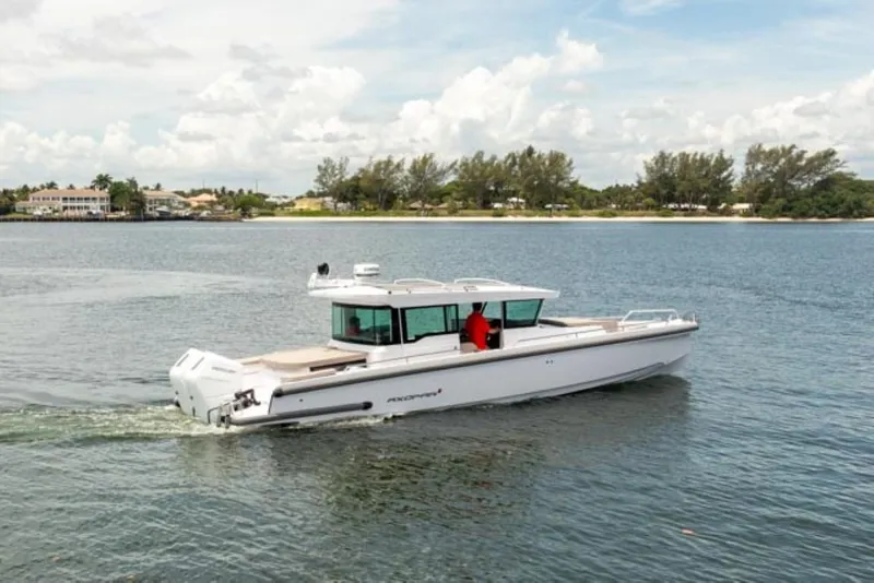 Slide: The Image of 2024 Axopar 37XC CROSS CABIN cruising on a calm lake under a partly cloudy sky. - 1