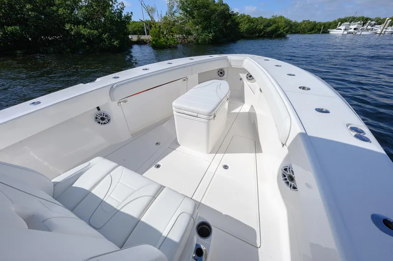 Slide: The Image of 2025 SeaVee 370Z boat interior with seating, speakers, and storage, docked by lush greenery. - 7