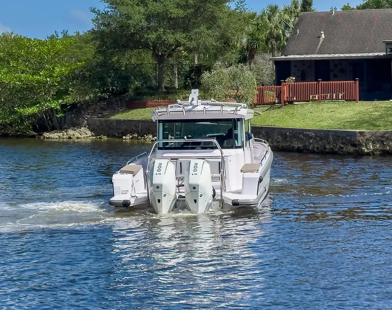 Slide: The Image of 2024 Axopar 37XC CROSS CABIN boat cruising on a scenic waterway. - 37