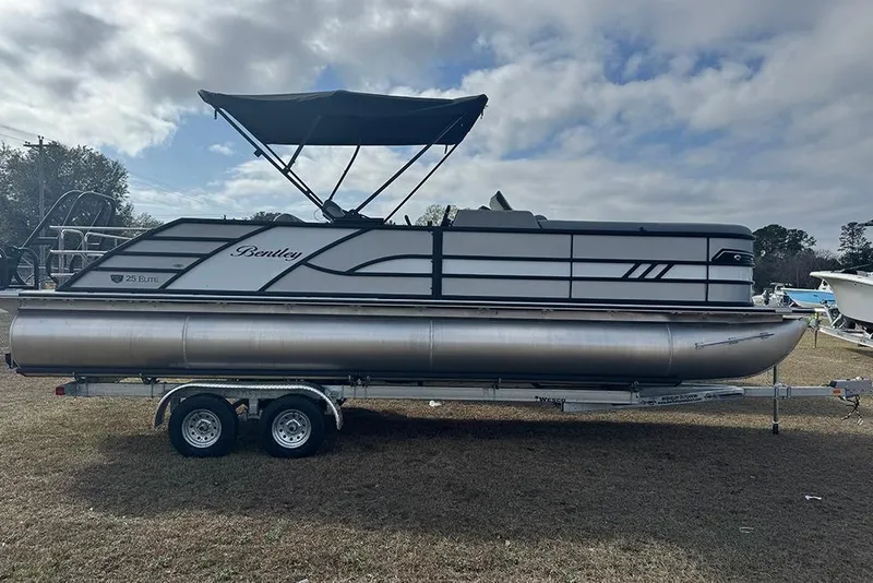 The Image of 2026 Bentley Pontoons Elite 253 Swingback Dual Captain Full Tritoon on trailer, side view. - 2