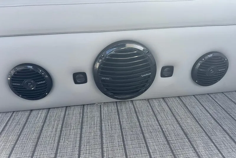 Slide: The Image of 2026 Bentley Pontoons Elite 253 Tritoon speakers on gray upholstery and textured flooring. - 31