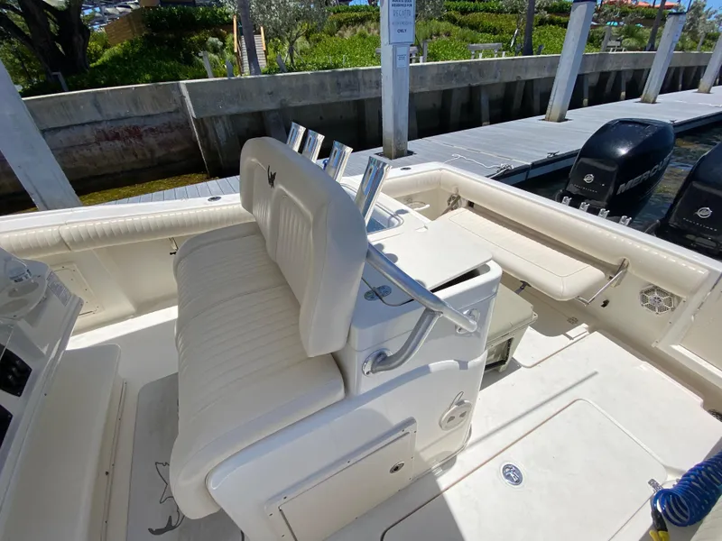 Slide: The Image of 2014 Mako 284 CC boat interior with white seating and docked at marina. - 14