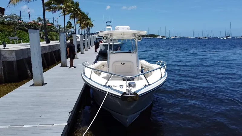 Slide: The Image of 2014 Mako 284 CC boat docked by a wooden pier on a sunny day. - 5