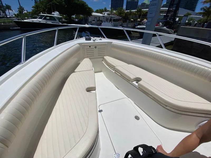 Slide: The Image of 2014 Mako 284 CC boat with spacious seating and sleek design at a marina. - 8