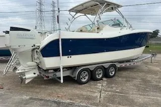 Slide: The Image of 2010 World Cat 290 DC boat on a triple-axle trailer, parked outdoors. - 2