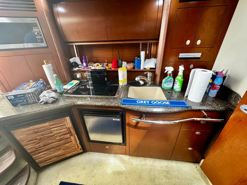 Slide: The Image of 2007 Sea Ray 40 Sundancer kitchen with appliances, cleaning supplies, and wooden cabinetry. - 23