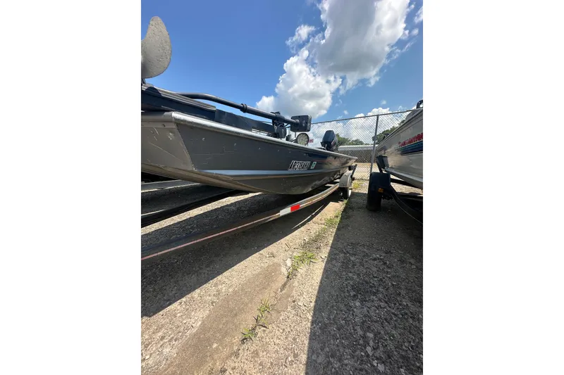 Slide: The Image of 1991 Grumman Rogue 150 T boat parked on concrete under a blue sky. - 11