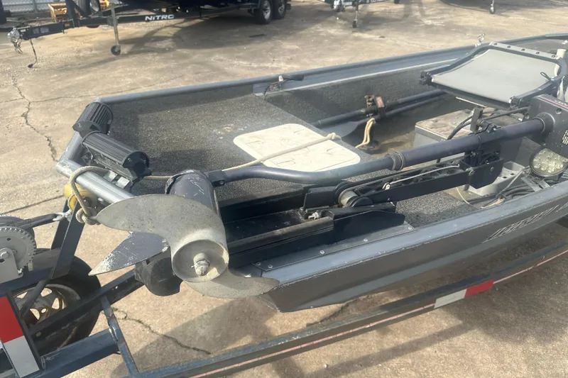 Slide: The Image of 1991 Grumman Rogue 150 T boat with motor and trailer, parked on concrete. - 7