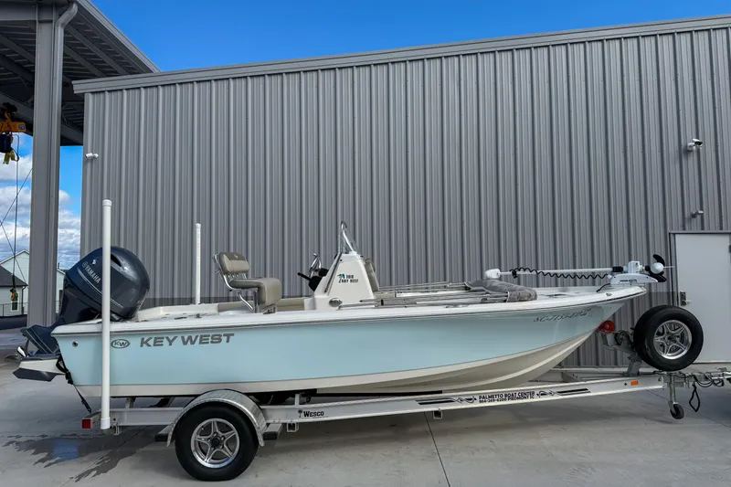 Slide: The Image of 2022 Key West 188 Bay Reef boat on trailer, parked beside a metal building. - 1