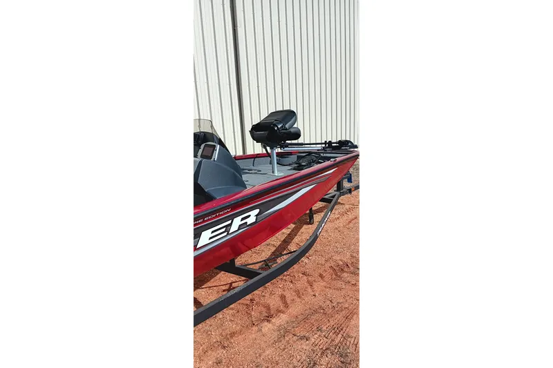 Slide: The Image of 2025 Tracker Pro Team 175 boat, red exterior, parked on sandy ground. - 18