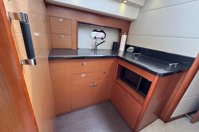 Slide: The Image of Compact kitchen area in a 2014 Prestige 400 yacht with modern amenities and wood cabinetry. - 17