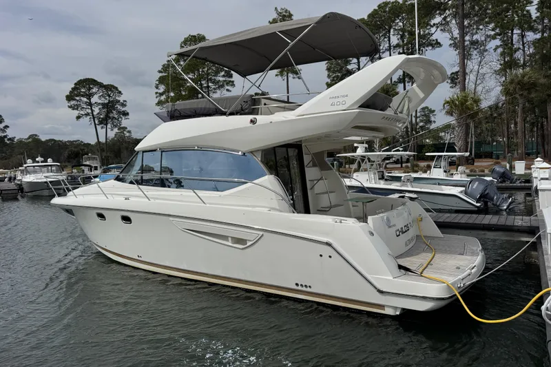 Slide: The Image of 2014 Prestige 400 yacht docked at marina, surrounded by trees and other boats. - 2