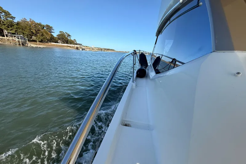 Slide: The Image of 2014 Prestige 400 yacht cruising on a serene waterway, clear blue sky above. - 34