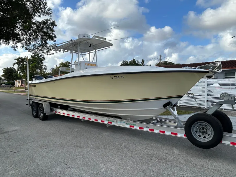 Slide: The Image of 2001 Contender 27' cuddy boat on trailer, parked on street under cloudy sky. - 2