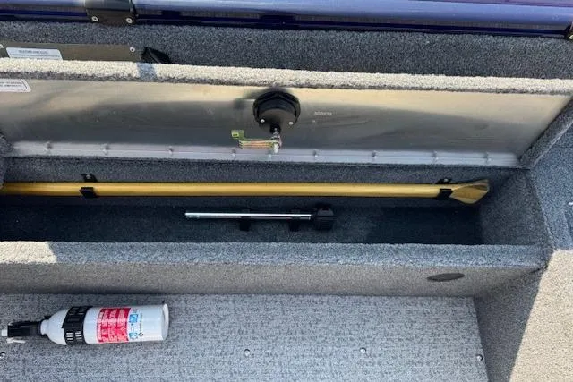 Slide: The Image of 2023 Tracker Pro Guide V-16 WT boat storage compartment with paddle and fire extinguisher. - 17