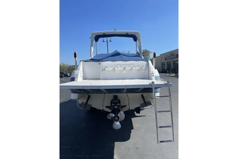Slide: The Image of 1993 Monterey 250 Cruiser boat, rear view with ladder and covered deck, parked outdoors. - 2