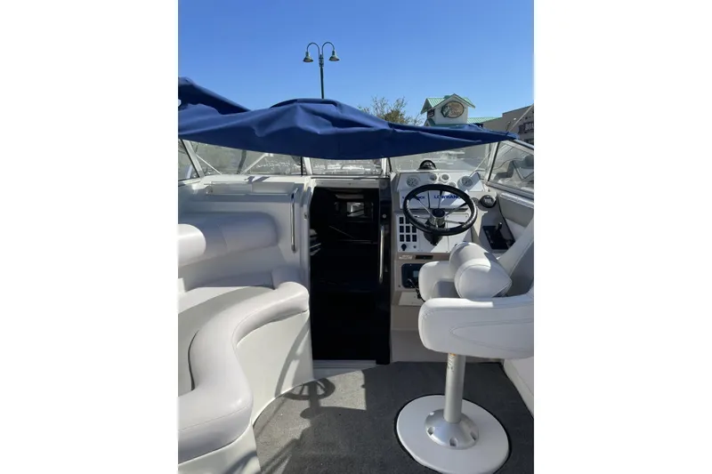 Slide: The Image of 1993 Monterey 250 Cruiser boat interior with steering wheel and seating under blue canopy. - 4