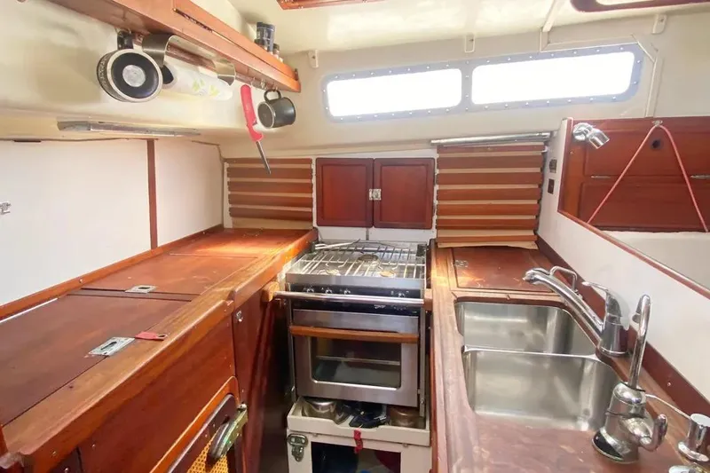 Slide: The Image of 1975 Whitby 42 Ketch interior kitchen with stove, sink, and wooden cabinetry. - 8