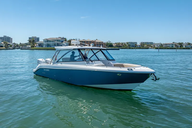 Slide: The Image of 2019 Everglades 340 Dual Console boat on calm water, coastal homes in background. - 0
