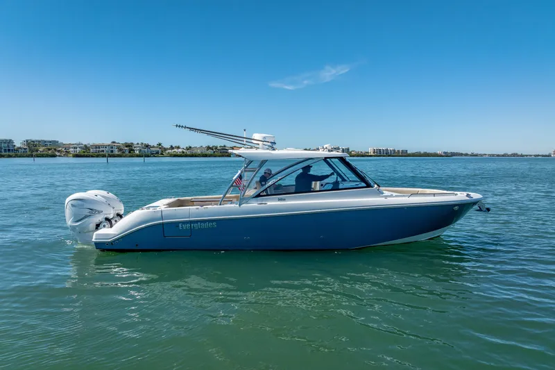 Slide: The Image of 2019 Everglades 340 Dual Console boat on calm water under clear blue sky. - 1