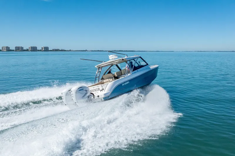 Slide: The Image of 2019 Everglades 340 Dual Console boat cruising on clear blue water. - 14