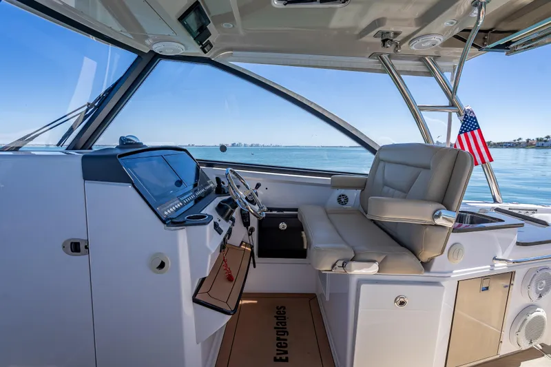 Slide: The Image of 2019 Everglades 340 Dual Console boat interior with helm and seating, overlooking calm waters. - 28