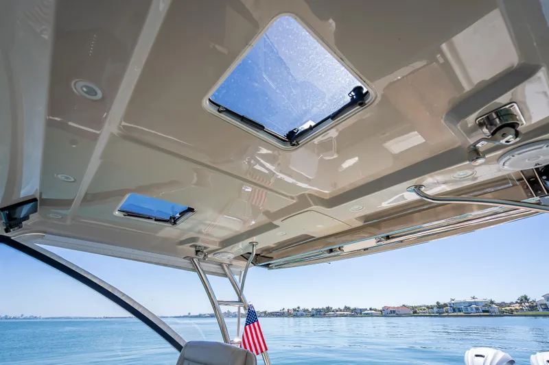 Slide: The Image of Interior view of 2019 Everglades 340 Dual Console boat with open sunroof and ocean backdrop. - 33