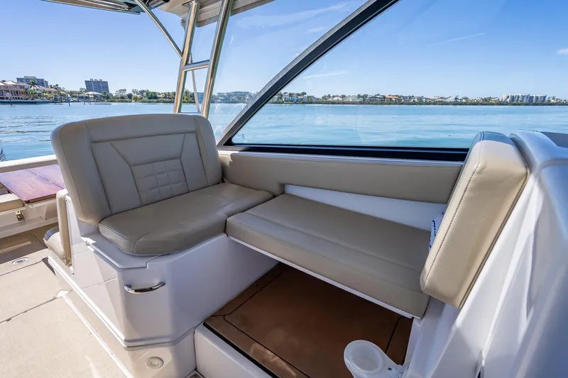 Slide: The Image of 2019 Everglades 340 Dual Console boat interior with beige seating and waterfront view. - 36