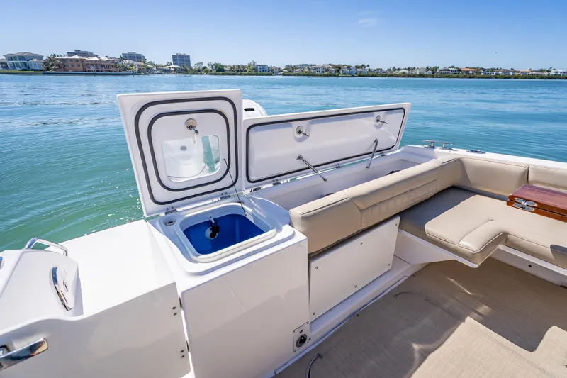Slide: The Image of 2019 Everglades 340 Dual Console boat interior with open storage and seating, near waterfront homes. - 44