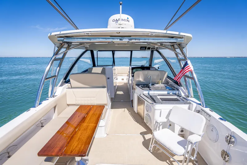 Slide: The Image of 2019 Everglades 340 Dual Console boat interior with seating, table, and ocean view. - 46