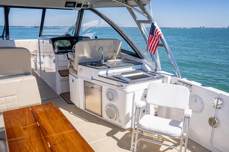 Slide: The Image of 2019 Everglades 340 Dual Console boat interior with seating and kitchenette on open water. - 49