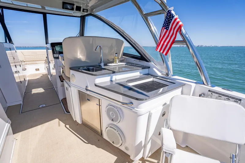 Slide: The Image of 2019 Everglades 340 Dual Console boat interior with kitchenette and American flag. - 50