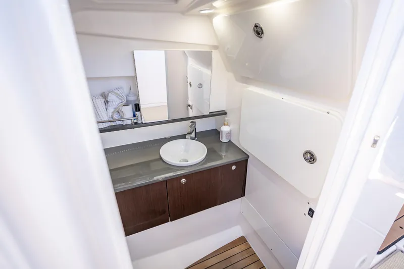 Slide: The Image of 2019 Everglades 340 Dual Console boat bathroom with sink, mirror, and storage cabinets. - 58