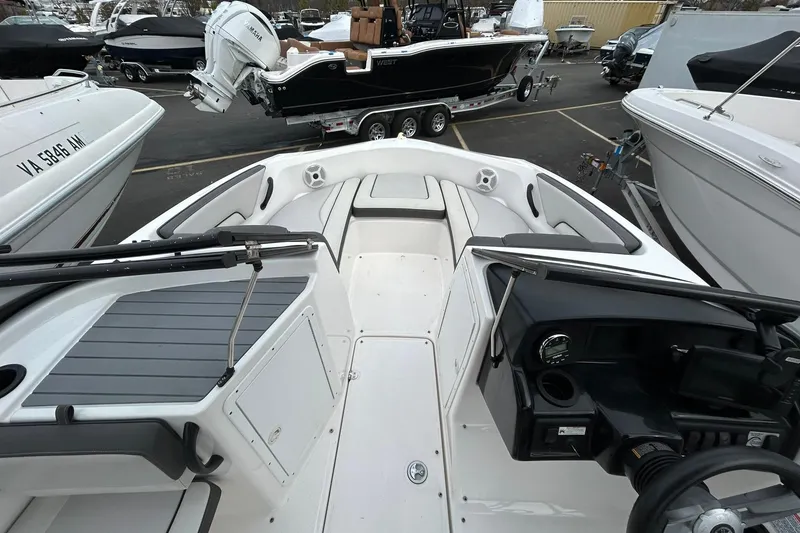 Slide: The Image of 2019 Yamaha Boats AR190 interior view, showcasing seating and dashboard in a marina setting. - 13