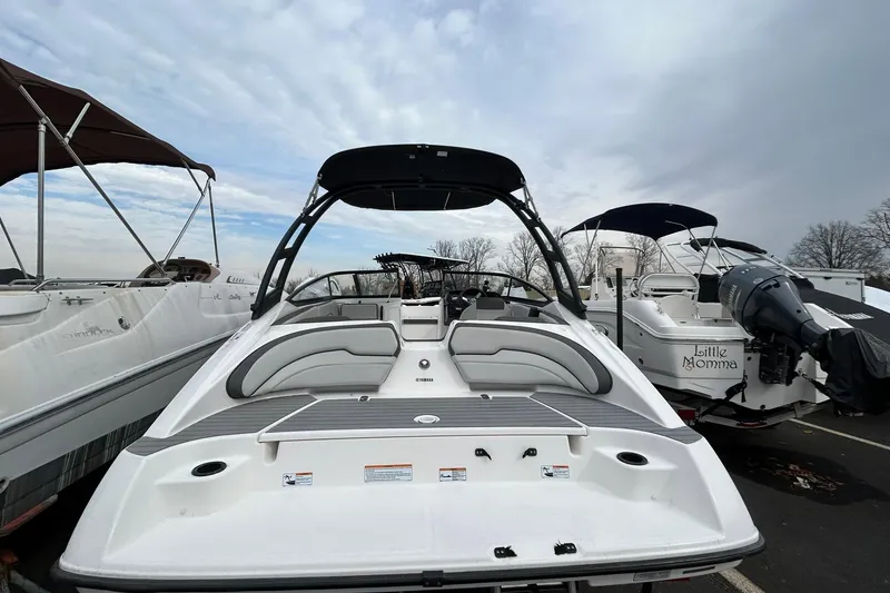 Slide: The Image of 2019 Yamaha Boats AR190, white, parked among other boats under a cloudy sky. - 2